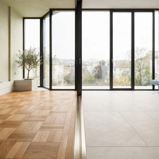 Parquet en chêne et carrelage clair se rejoignent près d’une grande baie vitrée.